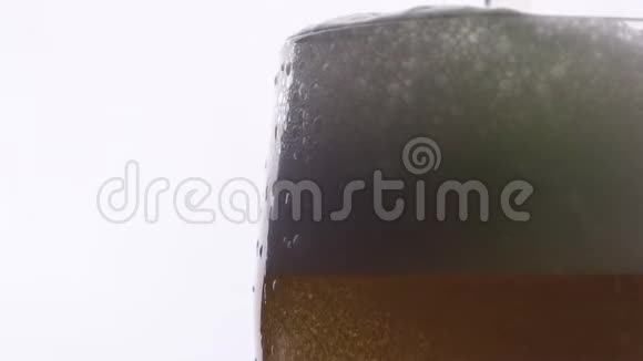 白色背景上有啤酒的玻璃中冒出细泡啤酒杯特写镜头慢动作泡沫7视频的预览图