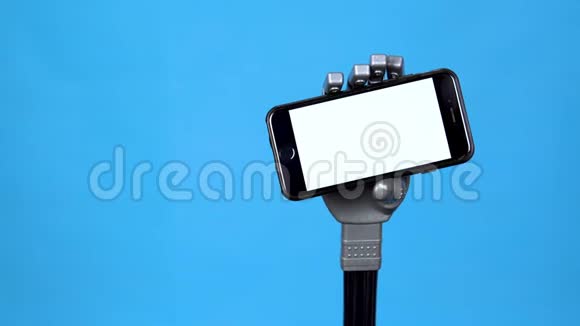 一只机械手拿着一个白色屏幕的手机灰色半机人手拿着蓝色背景的智能手机视频的预览图