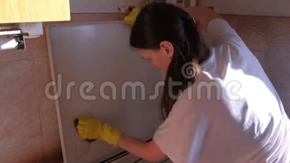 穿黄色橡胶手套的女人在厨房里洗脏的煤气炉金属海绵视频的预览图