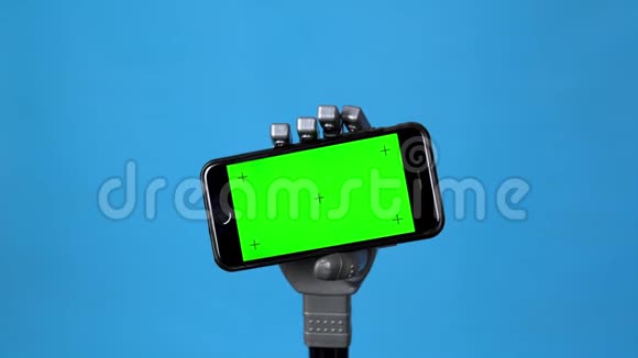 一只机械手拿着一个绿色屏幕的手机灰色半机人手拿着一部蓝色背景的智能手机铬视频的预览图