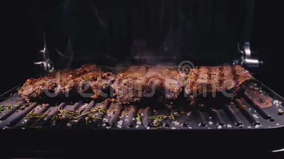 美味多汁的肉排在烤架上烹饪最珍贵的烤烤牛肉电烤炉迷迭香黑胡椒视频的预览图