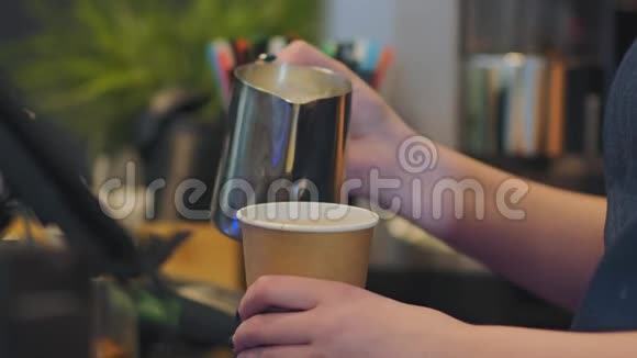 女咖啡师将热牛奶倒入纸杯特写镜头中视频的预览图