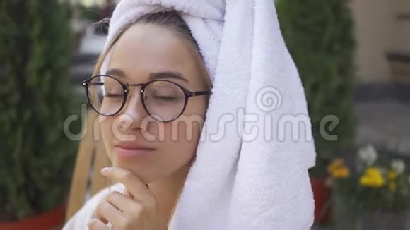 戴眼镜头戴毛巾的可爱年轻女人的肖像自信的女孩享受着美丽的早晨视频的预览图