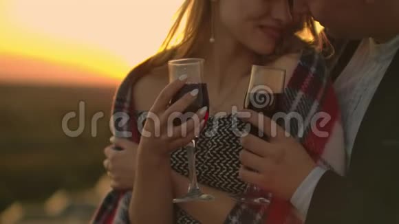 日落时分在阳台上举着红酒杯的女人的双手合拢庆祝理念视频的预览图