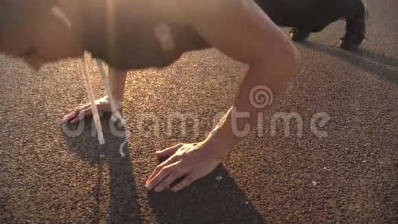 4k仍然是一个年轻的健身男子在傍晚在户外做俯卧撑的视频与强烈的太阳耀斑视频视频的预览图