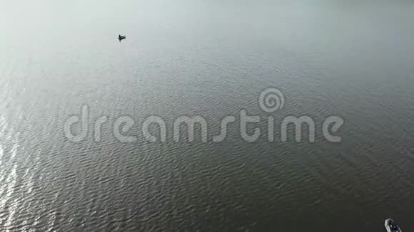 空中无人机在湖上的一艘小渔船上向渔民射击美丽的夏日风景湖鸟瞰图视频的预览图