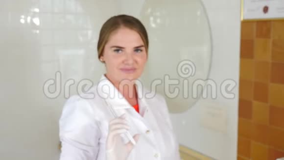 注射了集中的注射器穿着白色制服的模糊年轻女医生幸福微笑的女性美容师画像视频的预览图