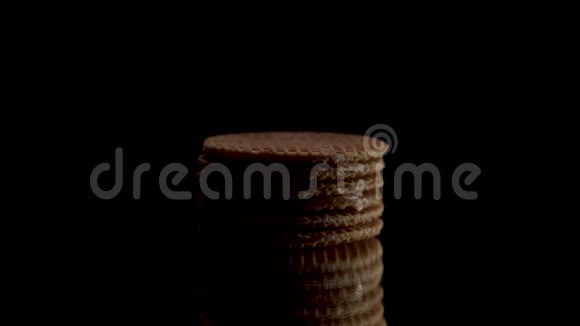 低键照明圆形华夫饼饼干的侧面视图在黑色背景上的黑色镜子上旋转或旋转甜甜饼视频的预览图