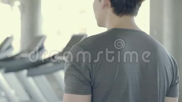 英俊的亚洲年轻人在健身房步行到跑步机亚洲男人在跑步机上锻炼有氧运动以促进健康视频的预览图