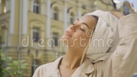 肖像微笑的年轻女子从她的头发上摘下毛巾一边站在上面一边高兴地笑着擦干毛巾视频的预览图