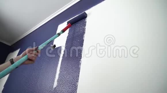 公寓里的房屋画家用滚筒把白色的墙涂成蓝色视频的预览图