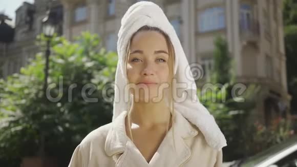 可爱的年轻女子的肖像头上有毛巾空中亲吻站在街上微笑着看镜头视频的预览图