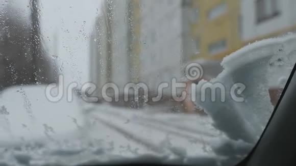 一块雪落在汽车的挡风玻璃上汽车雨刷开始清洗玻璃视频的预览图