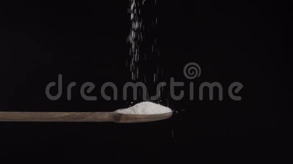 盐从上面倒进一个黑色背景的木勺7视频的预览图