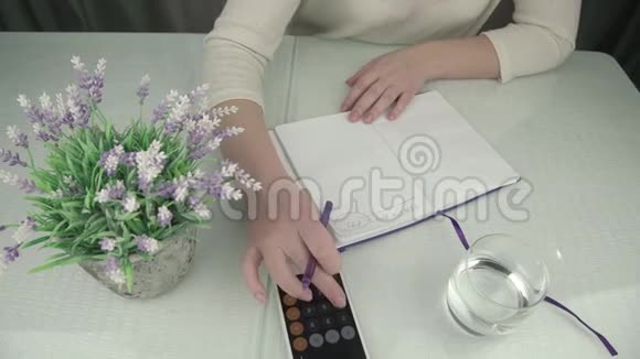 女士数着智能手机的书写和关闭紫色笔记本视频的预览图
