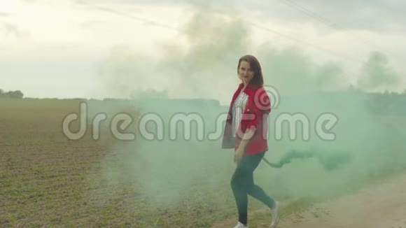 迷人的女人在田野中的彩烟中漫步视频的预览图
