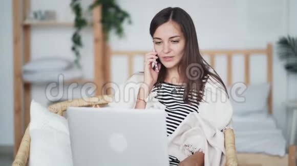 自由职业者使用笔记本电脑和智能手机在家工作在电话交谈视频的预览图
