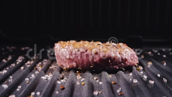 美味多汁的肉排在烤架上烹饪牛肉煎煮后缓慢倒入盐迷迭香黑胡椒视频的预览图
