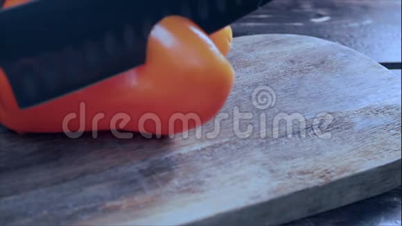 厨师用一张旧木桌在厨房的切板上切一个橙色的辣椒片视频的预览图
