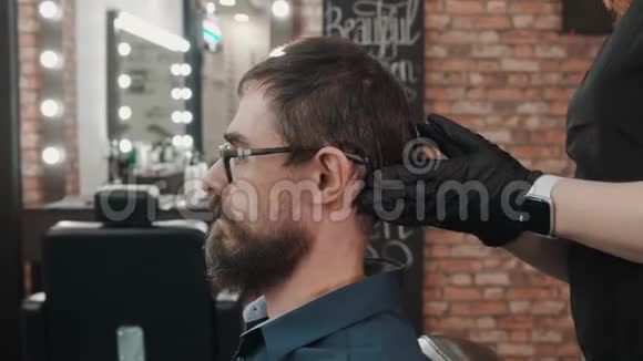 戴手套的理发师用弯针接触时尚男士的头部视频的预览图