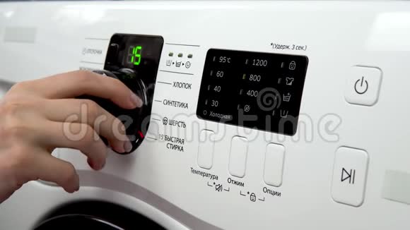 一个年轻的女人打开洗衣机一个女人转动杠杆选择洗衣机上的模式并转动它视频的预览图