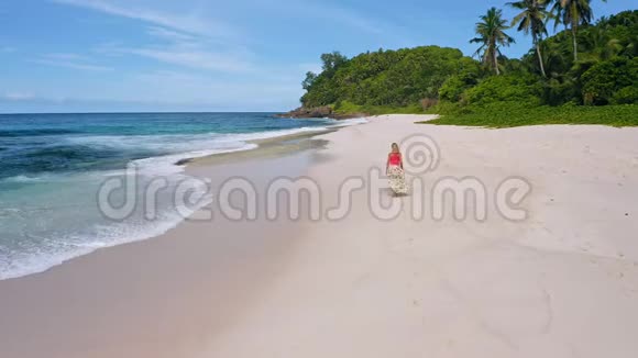 在天堂安塞巴扎卡海滩上一名年轻女子走在镜头前空中4k镜头拍摄的晒黑女孩视频的预览图
