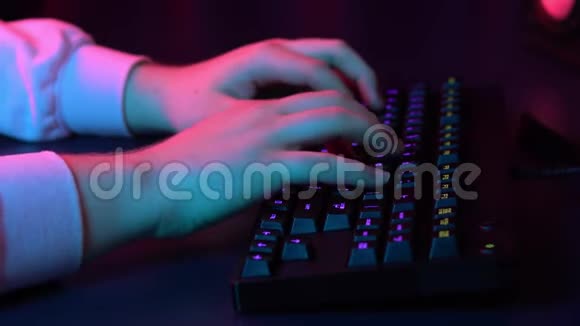 一个年轻人正在电脑键盘上打字把手举起来蓝红灯落在手上视频的预览图