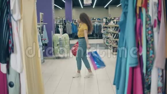 微笑的女人在服装店里拿着袋子旋转视频的预览图