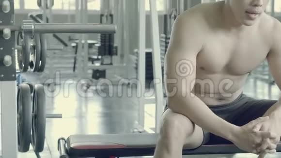 英俊的亚洲男人在健身房锻炼后肌肉发达疲劳乏力男人有汗休息视频的预览图