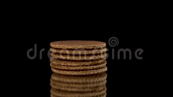 圆形华夫饼饼干的侧面视图在黑色背景上的黑色镜子上旋转或旋转桌上摆着甜甜饼视频的预览图