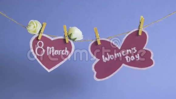 妇女节快乐妇女节在粉红色的纸上挂在一根绳子上靠近一颗粉红色的心上面装饰着鲜花蓝色视频的预览图