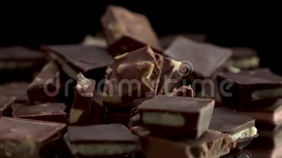 在黑色背景的桌子上关闭旋转的巧克力片的视图很多不同的巧克力块视频的预览图