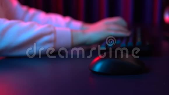 一个年轻人在电脑键盘上打字用鼠标工作把手举起来蓝红灯落在手上视频的预览图
