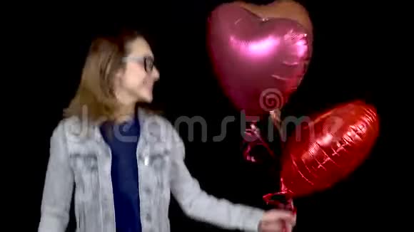 一个年轻的女孩站着心形的气球女人高兴得跳起来手里拿着氦气球视频的预览图