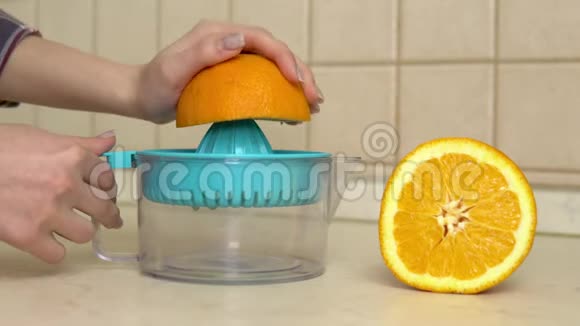 一个女人从橘子里榨果汁女人用榨汁机把手举起来视频的预览图