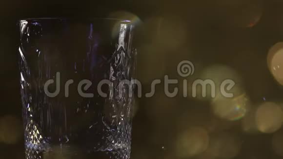 特写镜头威士忌酒杯的侧面VIEW将苏格兰威士忌或白兰地倒入装有冰块的玻璃杯中放在深色视频的预览图
