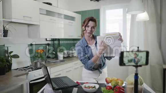 女性博客年轻迷人的家庭主妇保持博客谈论饮食计划和卡路里站在厨房视频的预览图