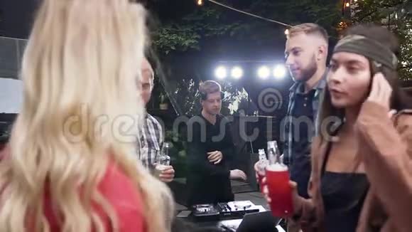 Dj音乐在户外晚会上被白种人的年轻朋友包围他们一起跳舞喝酒视频的预览图