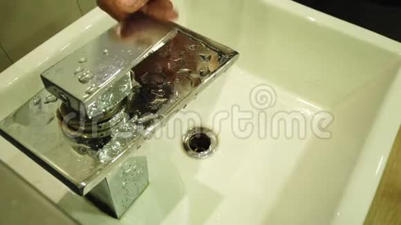 一名男子在水槽上打开水龙头洗手时被关闭视频的预览图