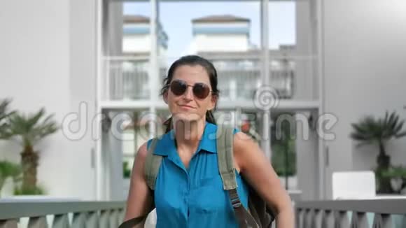 戴墨镜的嬉皮士女人在棕榈酒店后台慢跑视频的预览图