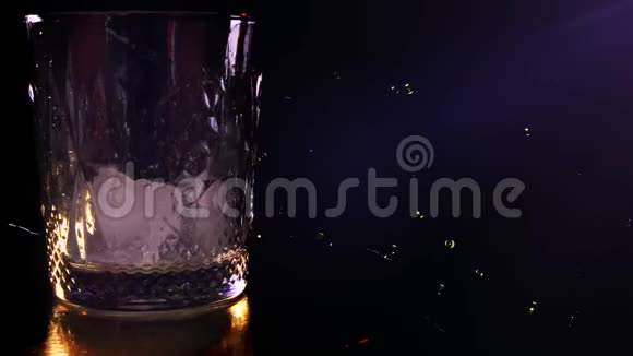 特写镜头威士忌酒杯的顶部将苏格兰威士忌或白兰地倒入装有冰块的玻璃杯中放在深色视频的预览图