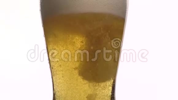 一杯啤酒的特写镜头在缓慢的运动中泡沫啤酒倒入装有白色泡沫的玻璃杯中视频的预览图