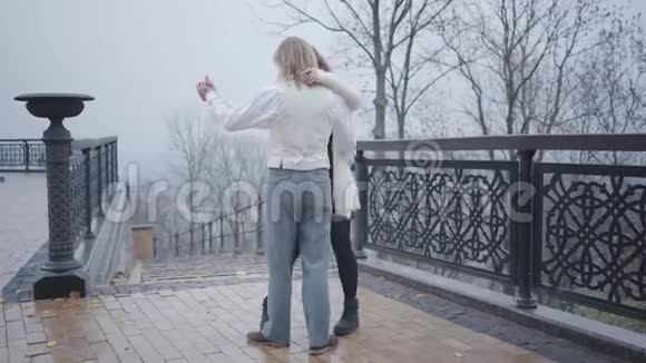 年轻漂亮的高加索夫妇在秋天公园的桥上跳舞穿着时尚的白色衬衫和背心的帅哥视频的预览图