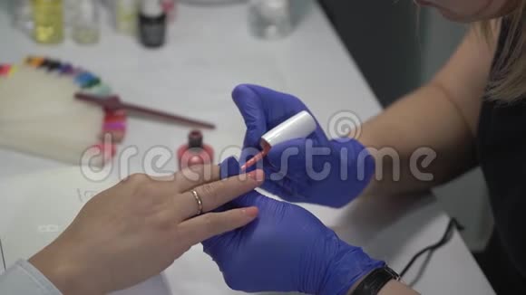 专业美甲师用彩色清漆覆盖指甲视频的预览图
