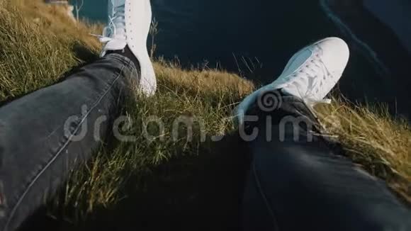 特写男腿穿着白色运动鞋在岩石边缘倾斜向上看史诗白海悬崖在奇妙的埃特雷特法国视频的预览图