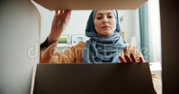 中东女人戴头巾打开纸盒微笑着接受礼物视频的预览图