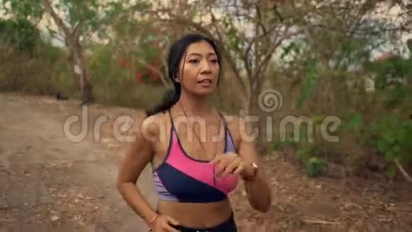 在农村公路户外慢跑锻炼中对年轻有魅力和异国情调的亚洲印尼跑步妇女进行慢动作吊臂跟踪视频的预览图