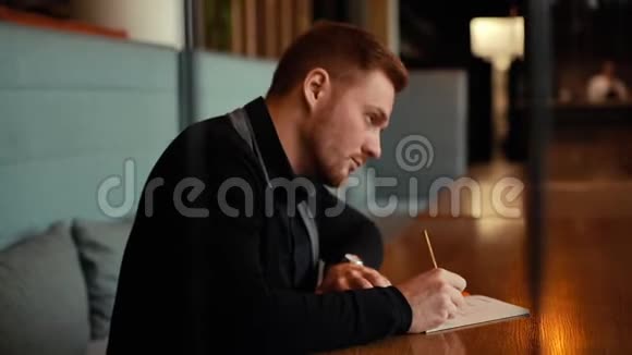 年轻的美女坐在咖啡馆里写在笔记本上视频的预览图