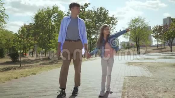 年轻的弟弟穿着时髦的衣服他可爱的小手牵着手在阳光明媚的秋天在公园里散步视频的预览图