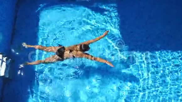不可辨认的漂亮女孩穿着黑色泳衣在豪华酒店的游泳池游泳年轻女子在温水中放松视频的预览图